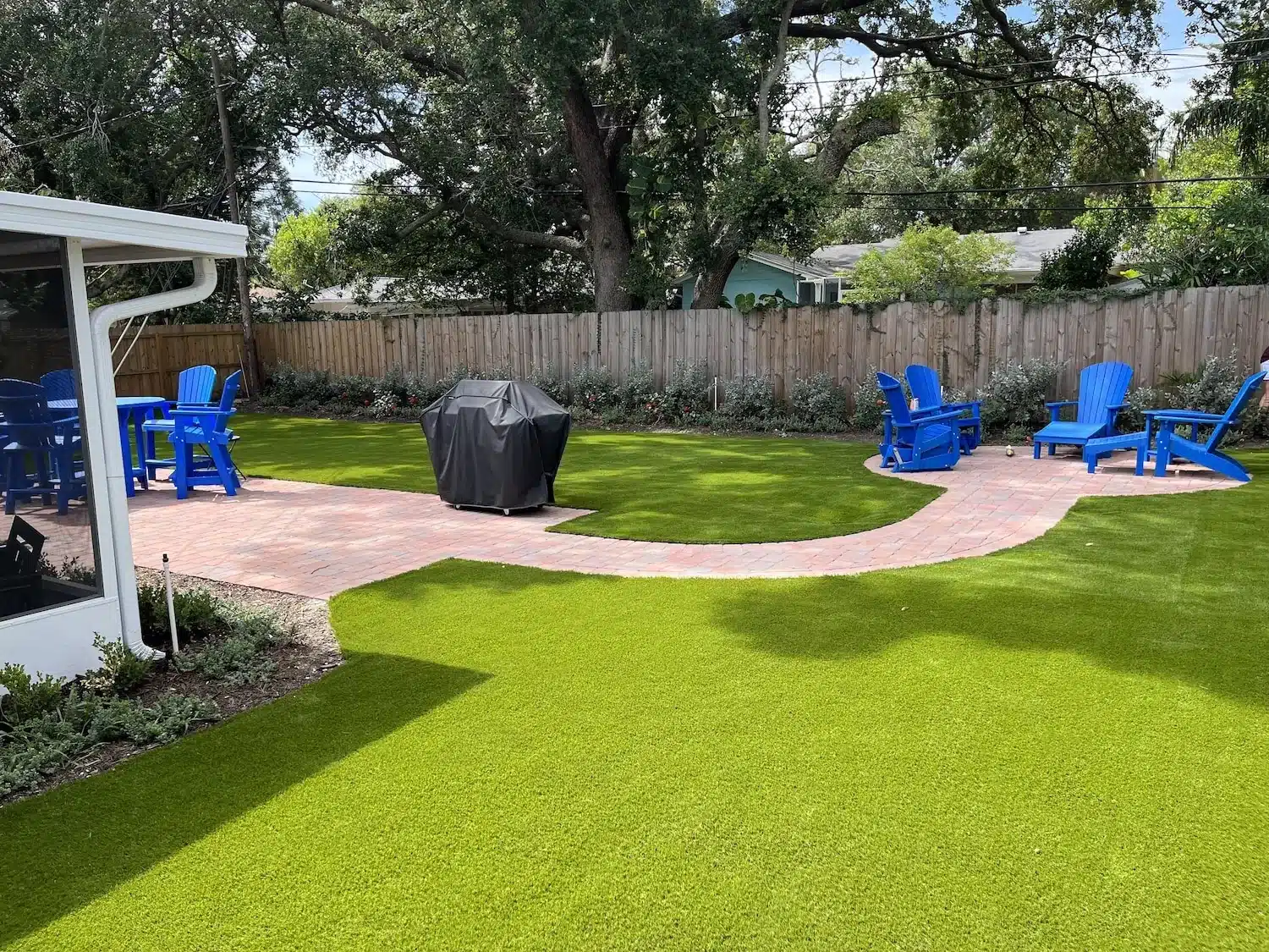 Artificial turf backyard with a paver path and clean landscape edging