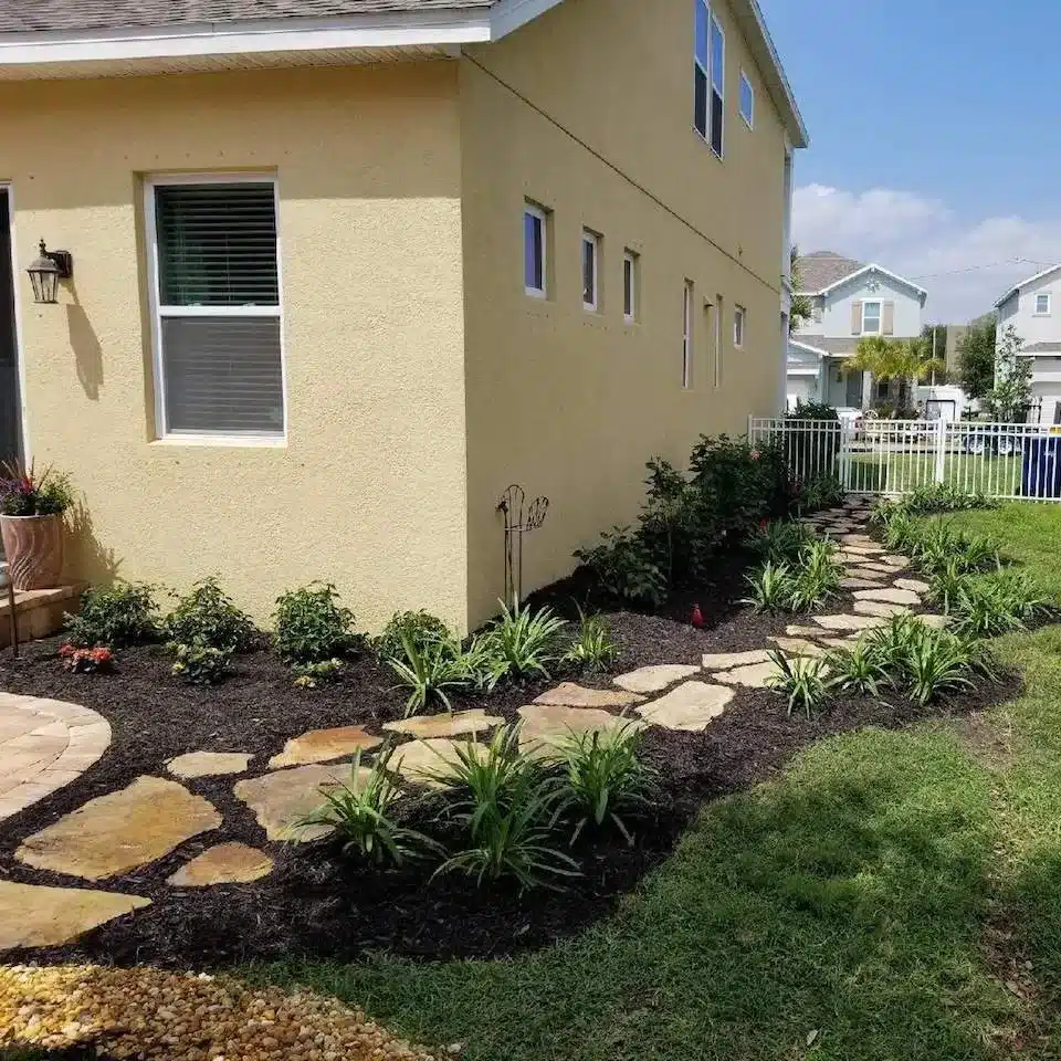 Flagstone path and new plantings along the side of a two-story home
