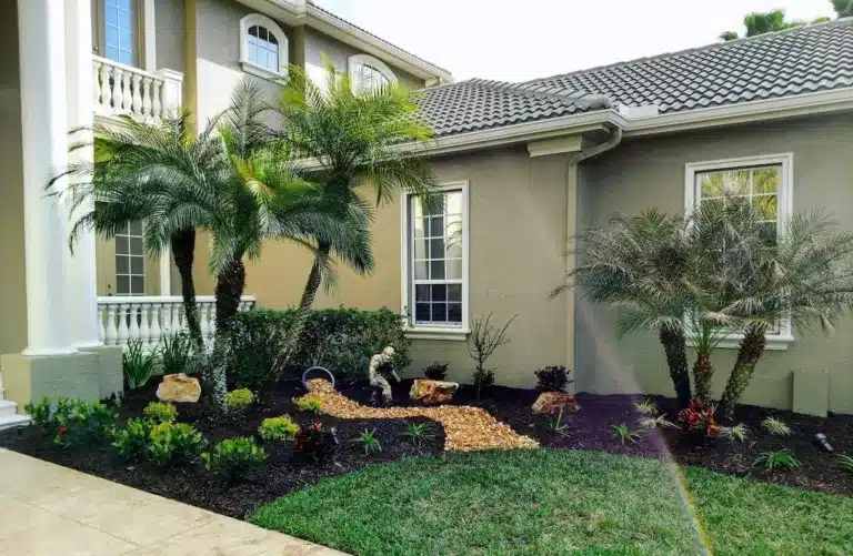 Front landscape beds with palms and mulch at a two-story home