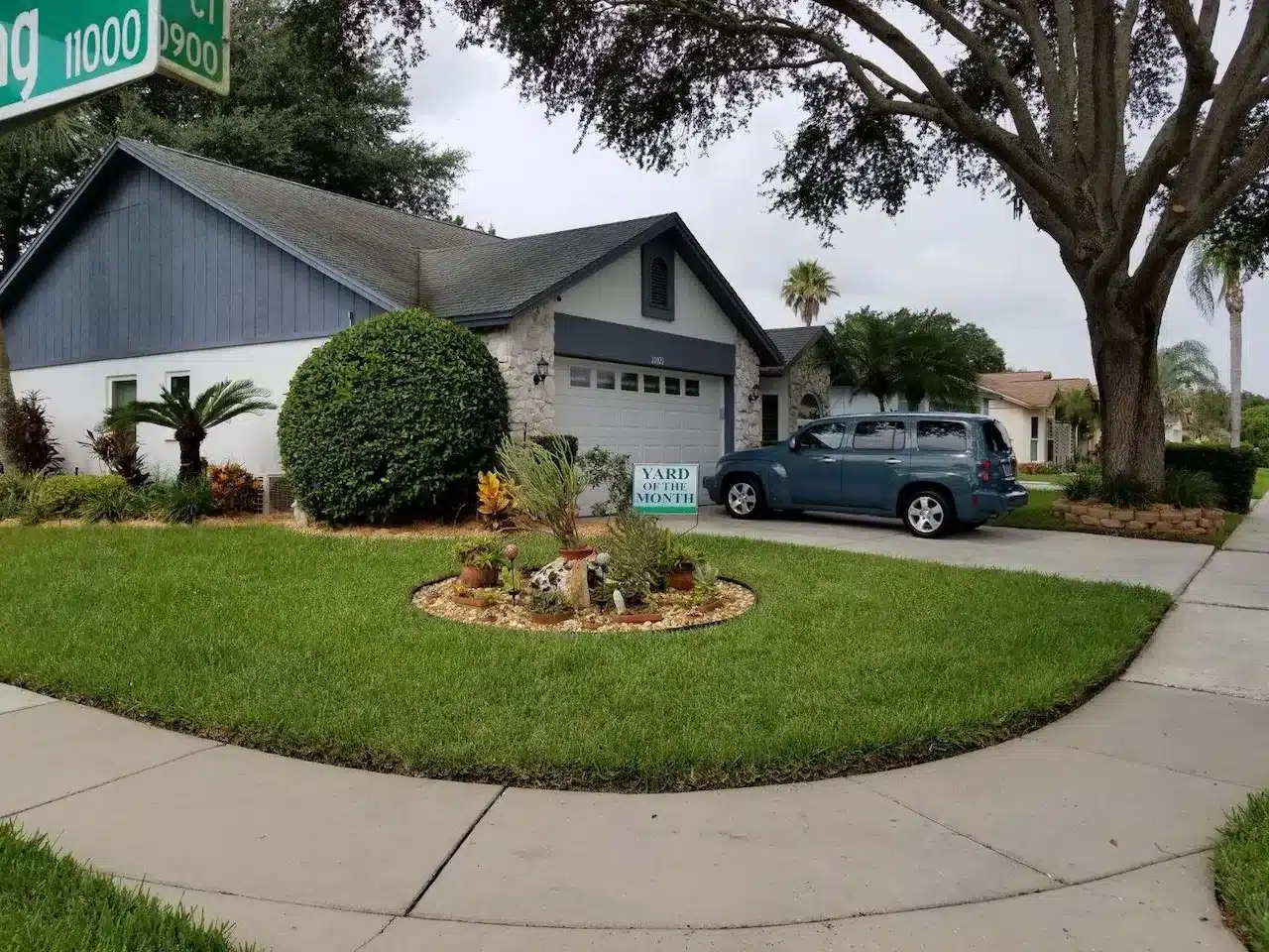 Front yard with trimmed lawn, round shrubs and a small island bed