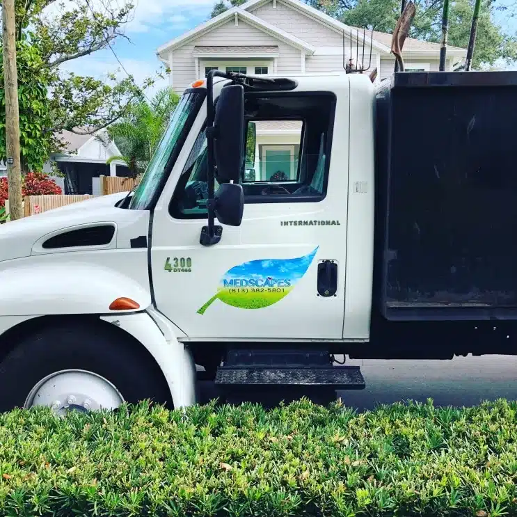 Medscapes work truck parked beside a trimmed hedge